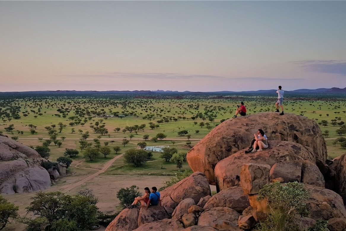 people on brown rock formation near green grass field during daytime